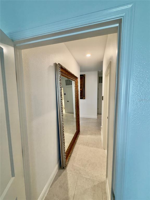 A hallway with light tile flooring features a large, ornate gold-framed floor mirror — 2098 GOLD DUST DRIVE, MINNEOLA, FL