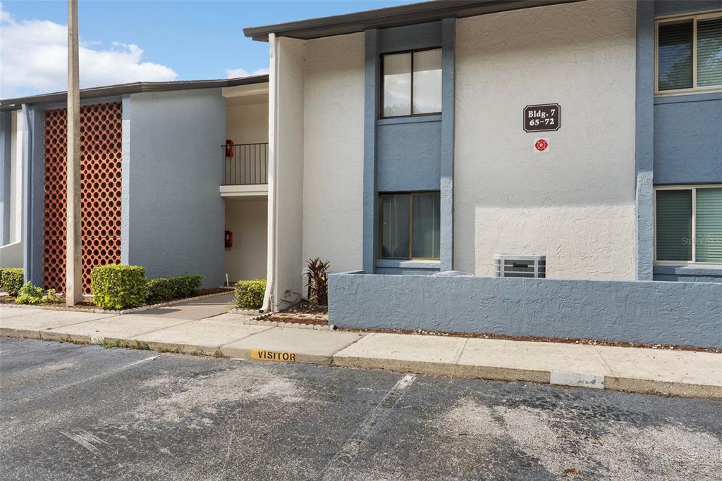 The exterior of a two-story apartment building features a decorative red brick screen wall — 7 ESCONDIDO CIRCLE UNIT 67, ALTAMONTE SPRINGS, FL
