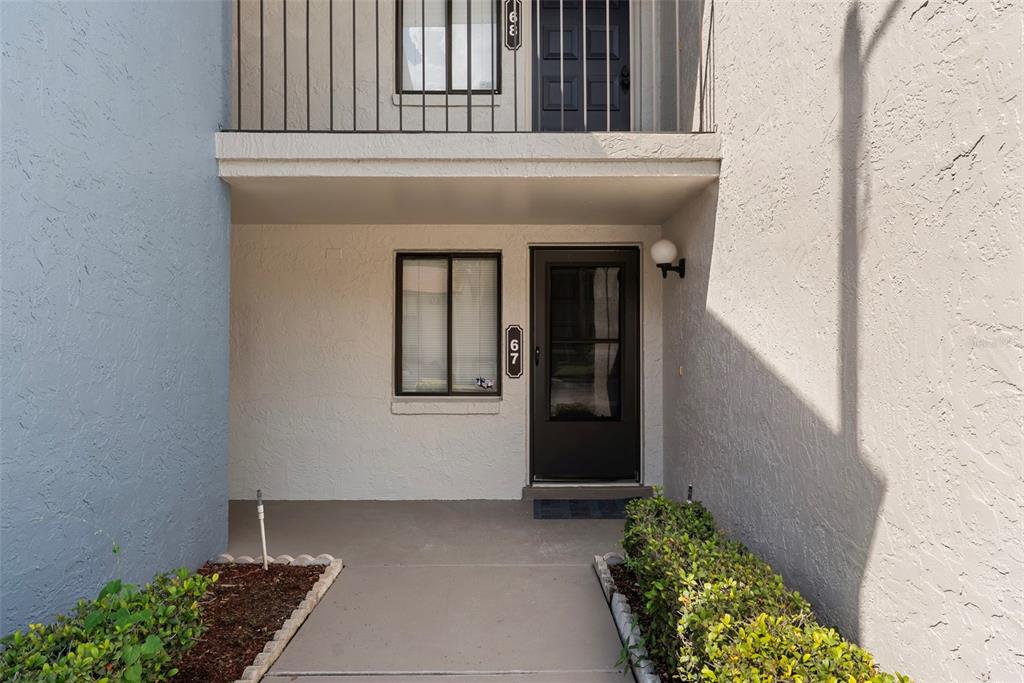 A view from a tiled entryway looking into a kitchen with white appliances and cabinets — 7 ESCONDIDO CIRCLE UNIT 67, ALTAMONTE SPRINGS, FL