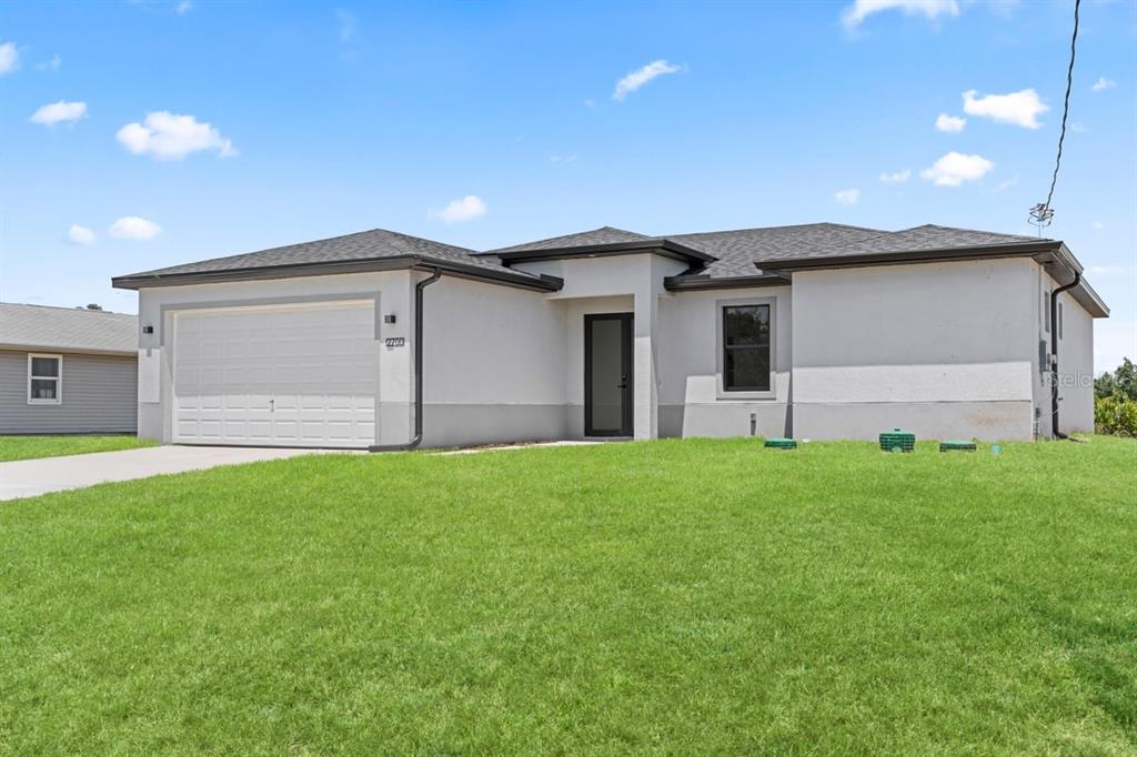 A single-story house with a white stucco exterior, a two-car garage, and a front entrance — 2700 69TH ST W, LEHIGH ACRES, FL