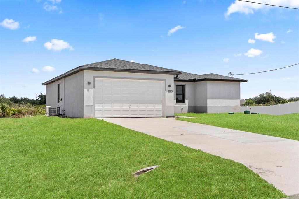 A single-story house with a white stucco exterior, a two-car garage, and a concrete driveway — 2700 69TH ST W, LEHIGH ACRES, FL