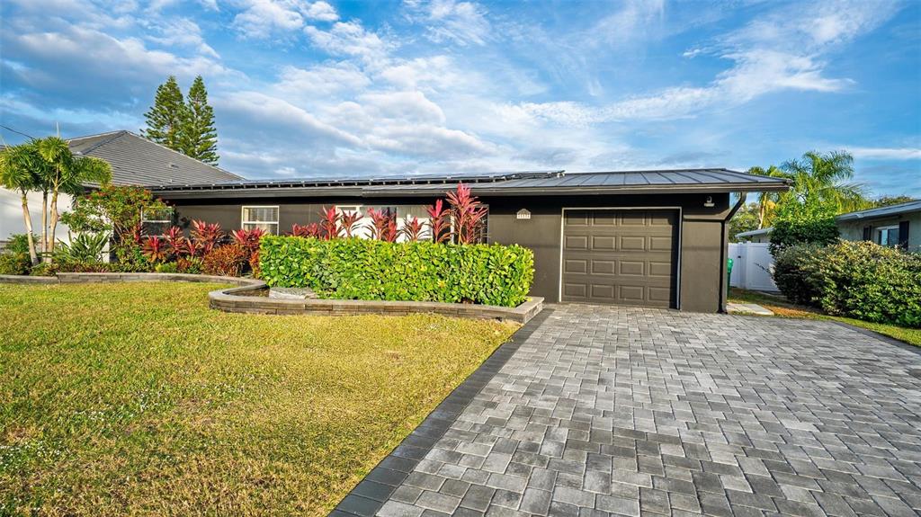 A single-story house with a dark exterior, a paved driveway, and a manicured hedge — 113 DELEON ROAD, COCOA BEACH, FL