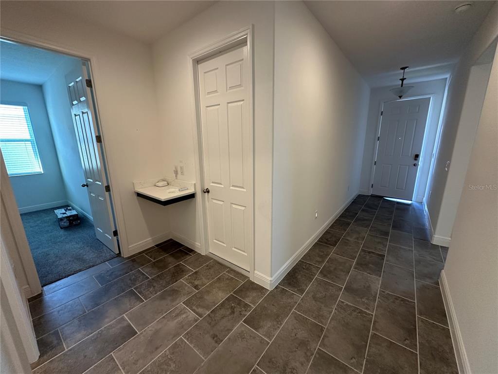 A hallway with tile flooring leads to an entryway door and a small built-in desk — 484 SHADOW GORGE WAY, EUSTIS, FL