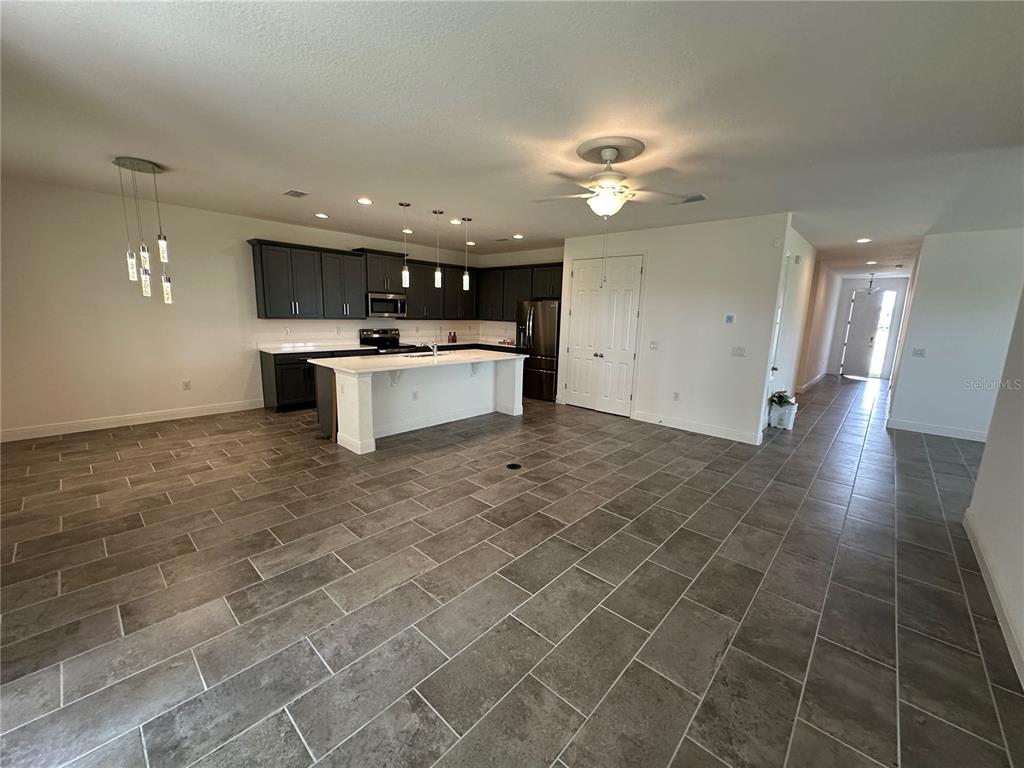 An open-concept kitchen features dark cabinets, a white island, and gray tile flooring — 484 SHADOW GORGE WAY, EUSTIS, FL