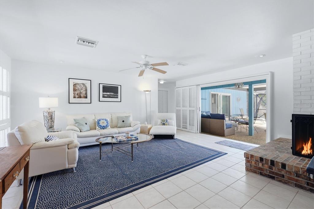 A living room features a brick fireplace, white tile floors, and sliding doors to a patio — 616 LYONS LANE, LONGBOAT KEY, FL