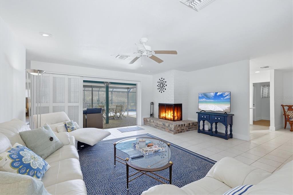 A living room features a white brick fireplace, tile floors, and sliding doors to a patio — 616 LYONS LANE, LONGBOAT KEY, FL