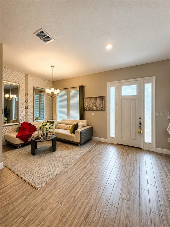 A living room features light wood-look tile flooring, a white sectional sofa, and textured walls — 6553 CYRILS DRIVE, ST CLOUD, FL