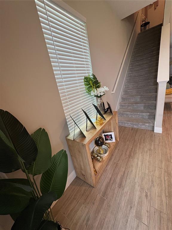 A wooden console table sits in a hallway with a staircase and wood-look flooring — 6553 CYRILS DRIVE, ST CLOUD, FL
