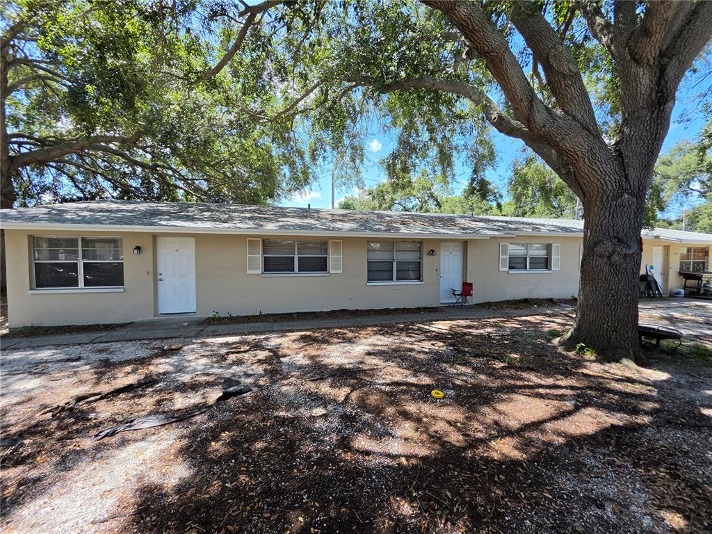 A single-story duplex with beige siding, white trim, and large trees in the front yard — 3735 141ST PLACE, LARGO, FL