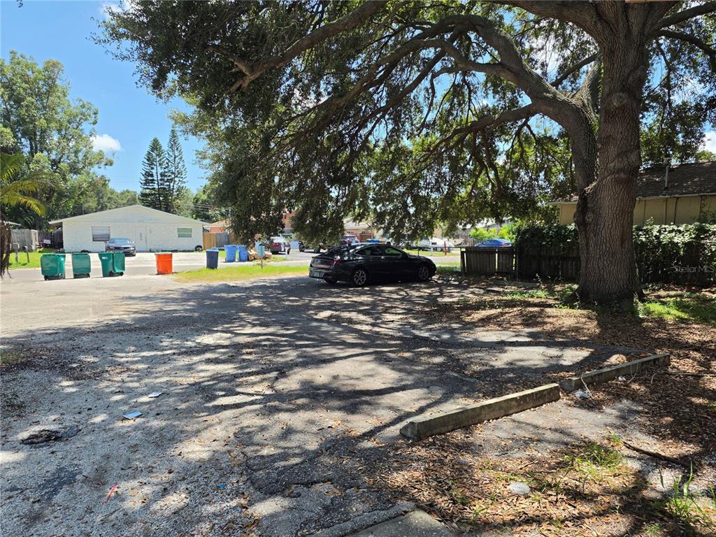 An unpaved parking lot with a large tree and several trash bins — 3735 141ST PLACE, LARGO, FL