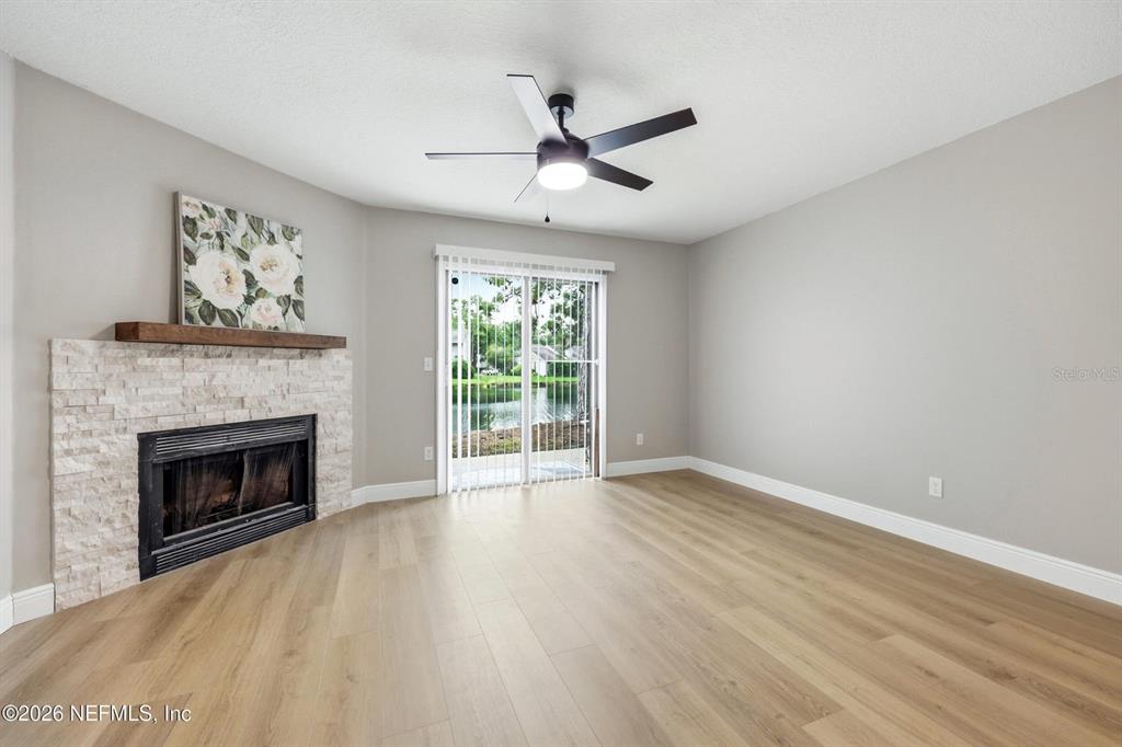 A living room features light wood flooring, a stone fireplace, and sliding glass doors — 3801 CROWN POINT ROAD UNIT 2093, JACKSONVILLE, FL
