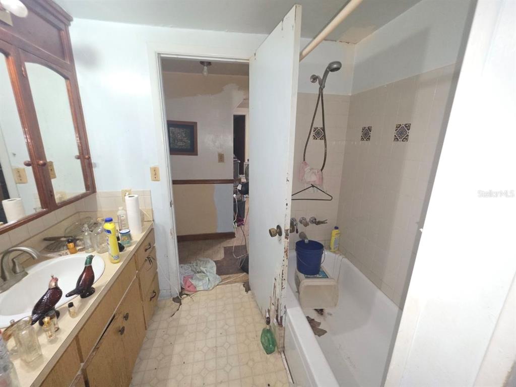 A bathroom features a vanity with a sink, a bathtub with a shower, and tile walls — 39521 COIT ROAD, DADE CITY, FL