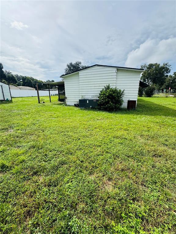 The exterior of a white mobile home features a side porch and an air conditioning unit — 1013 LIANNE PLACE, SEFFNER, FL