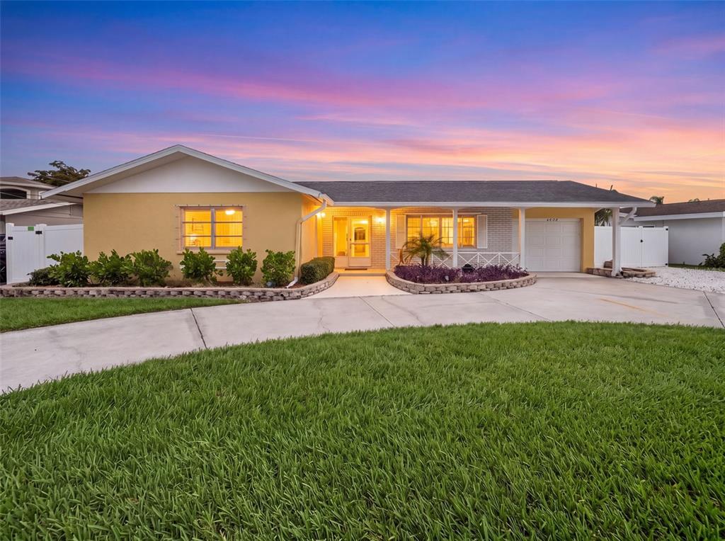 A single-story house with a yellow exterior, a concrete driveway, and a sunset sky — 4608 ARLINGTON ROAD, PALMETTO, FL