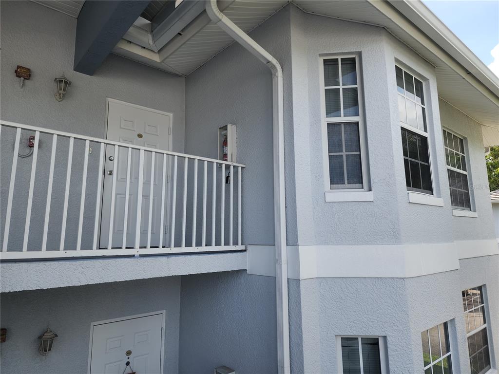 An exterior view of a two-story building with white railings, light gray stucco, and windows — 8416 BERNWOOD COVE LOOP UNIT 1612, FORT MYERS, FL