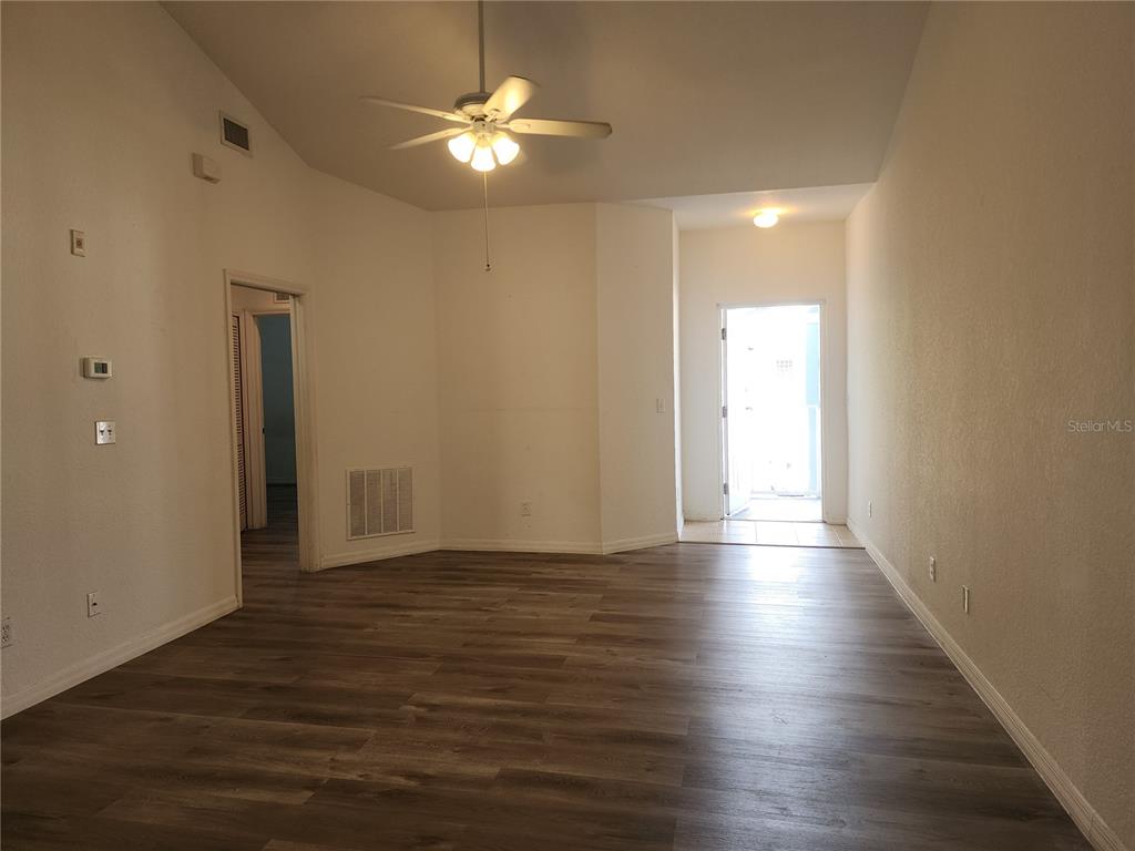 An empty room with wood-look flooring, a ceiling fan, and a doorway leading outside — 8416 BERNWOOD COVE LOOP UNIT 1612, FORT MYERS, FL
