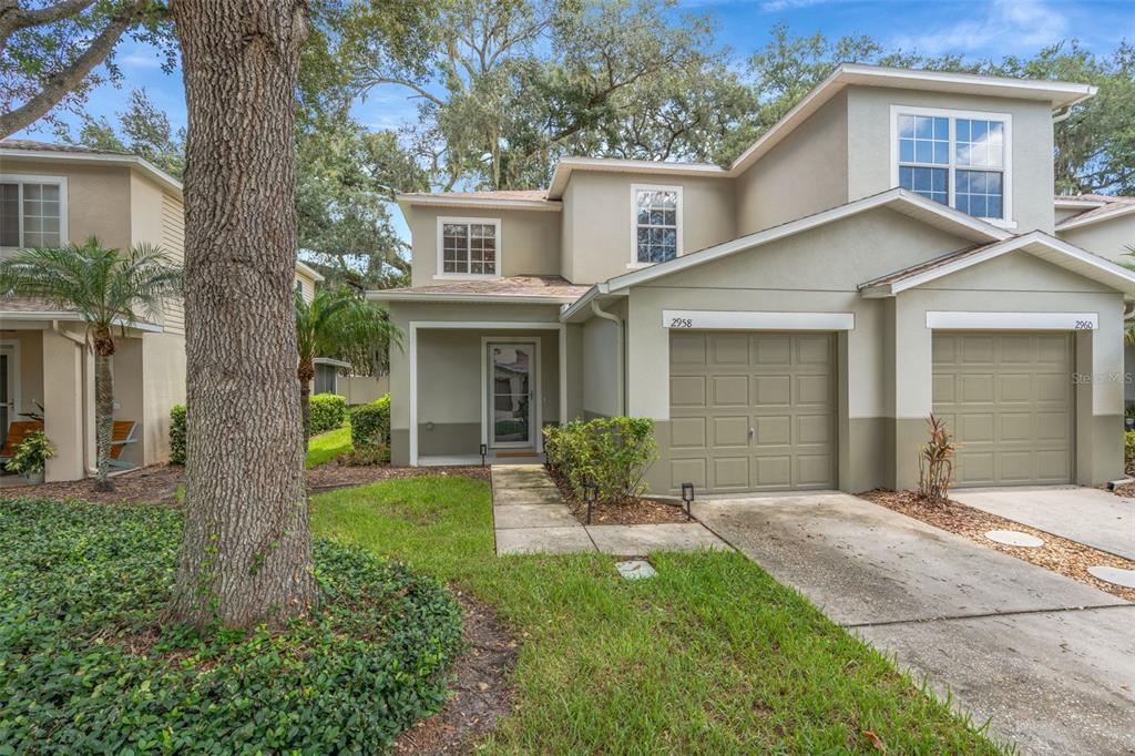 A two-story townhouse with a tan stucco exterior, a single-car garage, and a front walkway — 2958 ROYAL TUSCAN LANE, VALRICO, FL