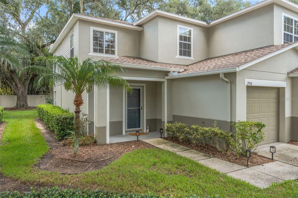A two-story townhouse exterior with a tan stucco facade, a small front porch, and garage — 2958 ROYAL TUSCAN LANE, VALRICO, FL