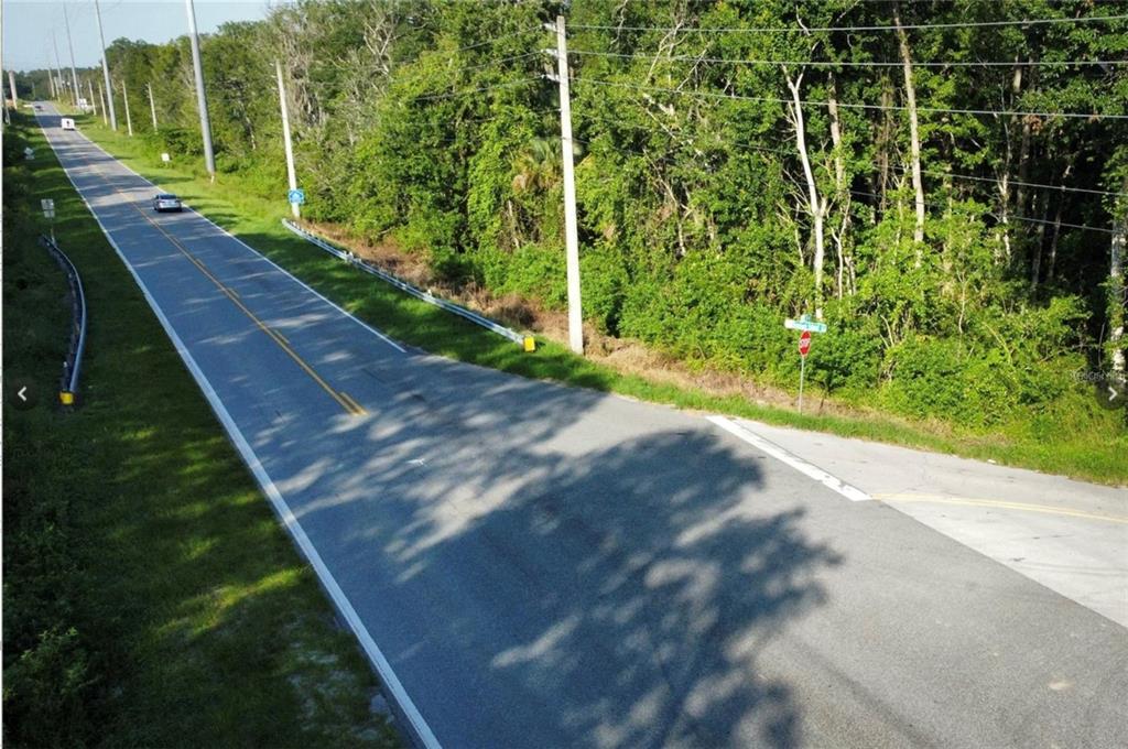 An aerial view of a paved road with a stop sign and surrounding wooded area — COUNTY ROAD 44, LEESBURG, FL