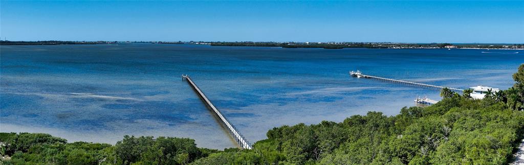 An aerial view of a long wooden pier extending into a calm blue bay — 8001 W 20TH PLACE, BRADENTON, FL