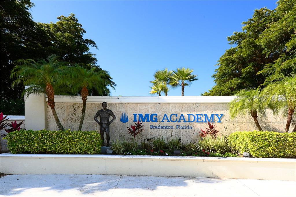 A stone wall with the IMG Academy logo and a statue stands amidst palm trees — 8001 W 20TH PLACE, BRADENTON, FL