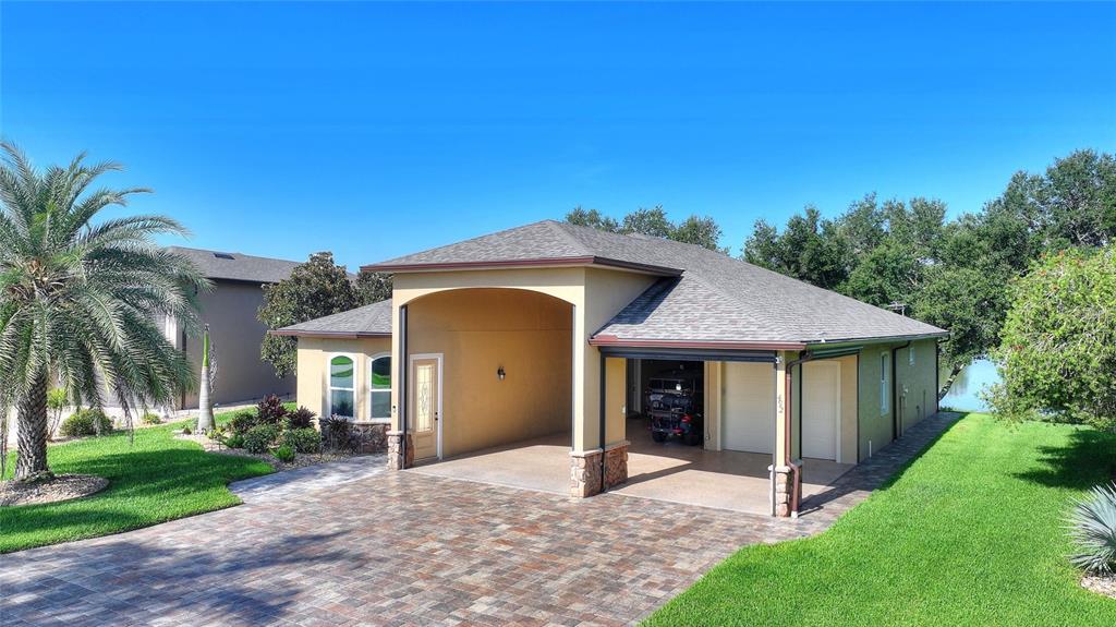 An exterior view of a house with a paved driveway, covered entryway, and attached garage — 492 MEANDERING WAY, POLK CITY, FL