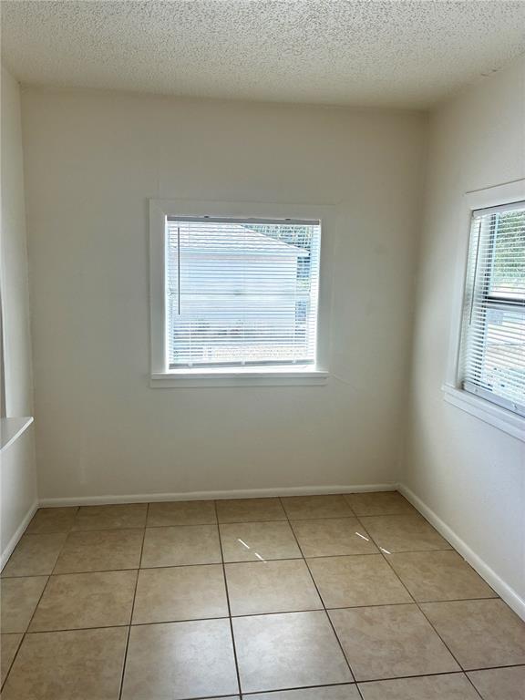 An empty room features beige tile flooring, white walls, and two windows with blinds — 3605 E 28TH AVENUE, TAMPA, FL