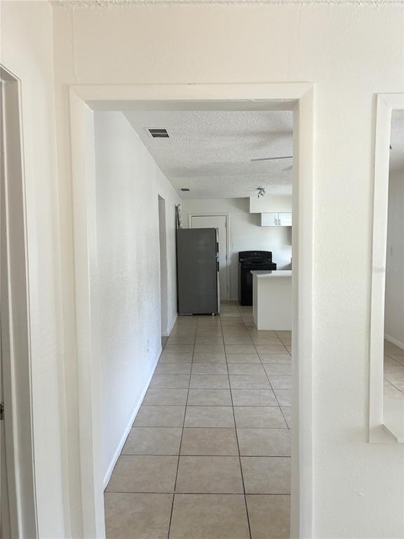 A view through a doorway shows a tiled kitchen with a refrigerator and stove — 3605 E 28TH AVENUE, TAMPA, FL