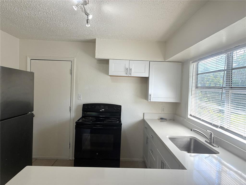 A kitchen features white cabinets, black appliances, a stainless steel sink, and a window — 3605 E 28TH AVENUE, TAMPA, FL