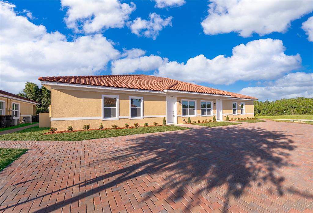 A single-story duplex with a terracotta tile roof and a brick paver driveway — 1661 CUMIN DRIVE, KISSIMMEE, FL