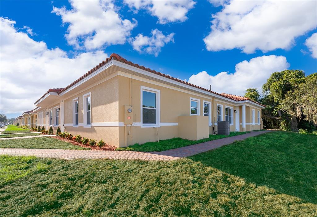 A tan, single-story residential building with a red tile roof and a brick walkway — 1661 CUMIN DRIVE, KISSIMMEE, FL