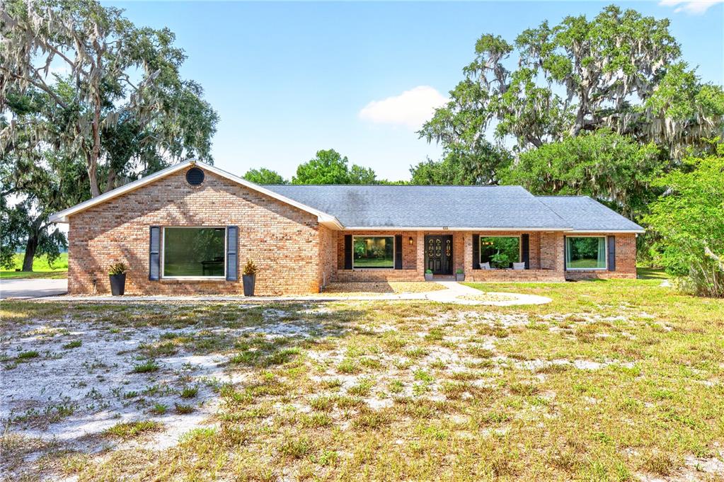 An aerial view shows a house with a pool on a large, partially wooded lot — 1600 E 10TH STREET, ST CLOUD, FL