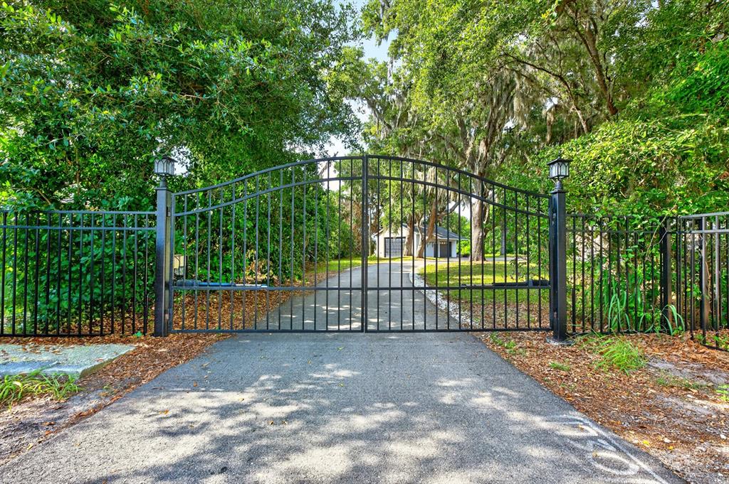 An aerial view shows a house with a pool, a pond, and surrounding trees — 1600 E 10TH STREET, ST CLOUD, FL