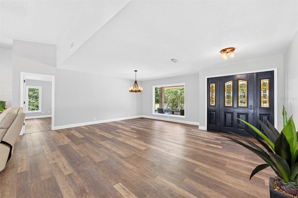 A covered patio with brick walls, ceiling fans, and a screened-in pool overlooking a field — 1600 E 10TH STREET, ST CLOUD, FL