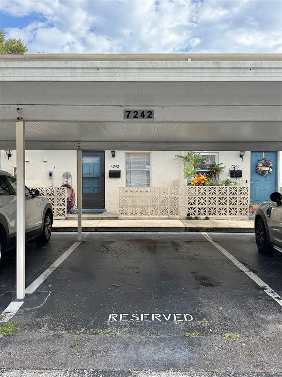 A covered parking space is situated in front of two residential units with decorative screens — 7242 STONE HAVEN COURT N UNIT 7242, PINELLAS PARK, FL