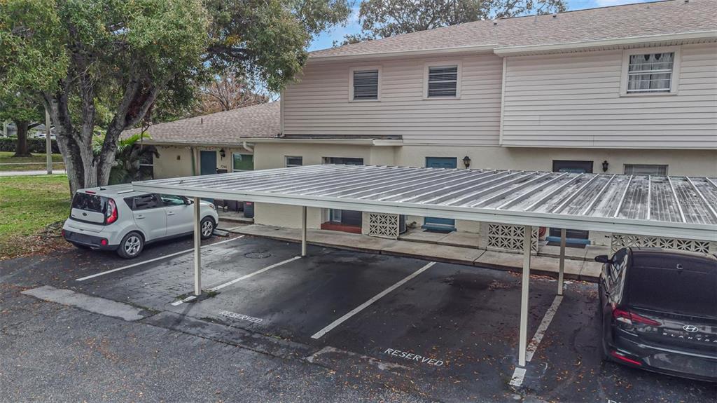 A two-story townhouse exterior features a metal carport covering reserved parking spaces — 7242 STONE HAVEN COURT N UNIT 7242, PINELLAS PARK, FL