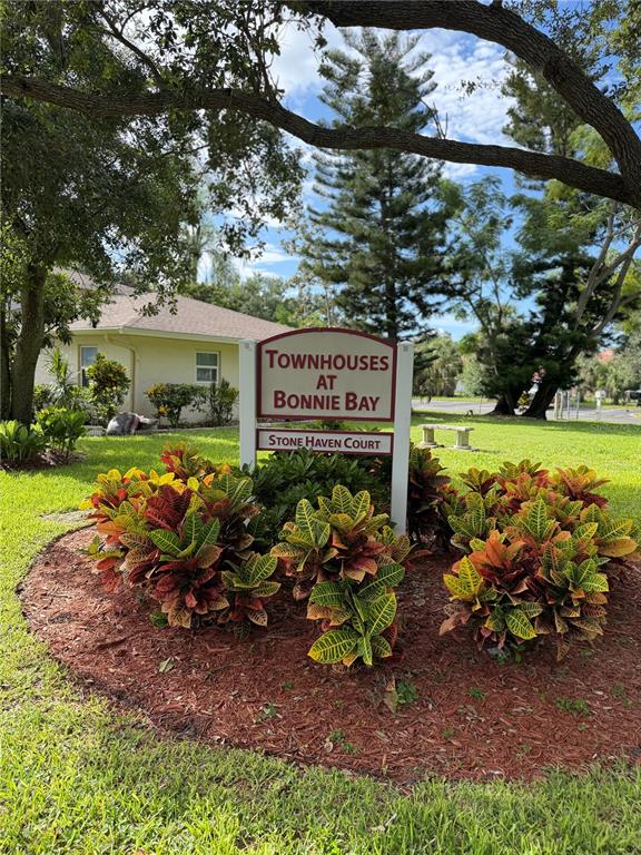 A sign for Townhouses at Bonnie Bay stands in a landscaped garden with colorful croton plants — 7242 STONE HAVEN COURT N UNIT 7242, PINELLAS PARK, FL