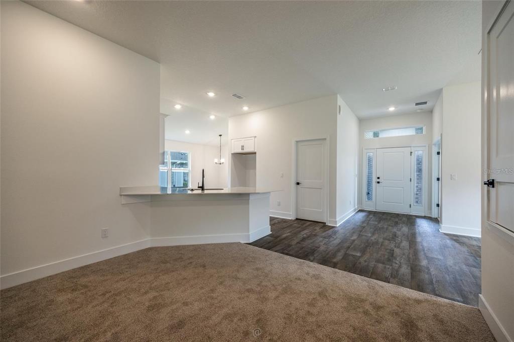 An interior view shows a carpeted living area transitioning to a kitchen with a breakfast bar — 32 RYMSHAW DRIVE, PALM COAST, FL
