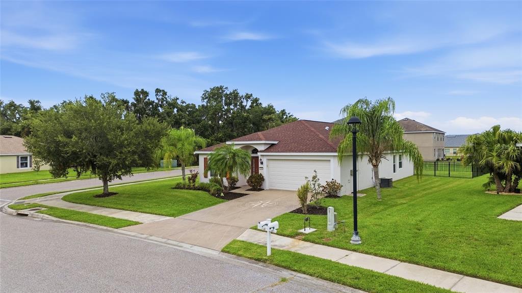 A single-story house with a brown roof, white garage, and palm trees in the yard — 9799 50TH STREET CIRCLE E, PARRISH, FL