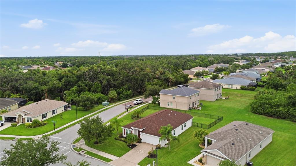 An aerial view shows several suburban houses with lawns and a wooded area nearby — 9799 50TH STREET CIRCLE E, PARRISH, FL