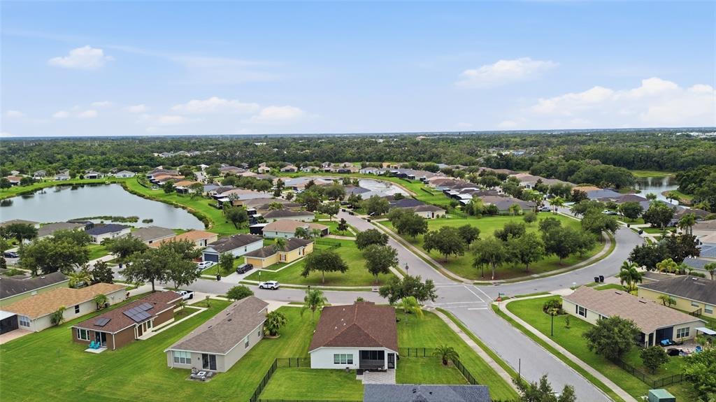 An aerial view of a suburban neighborhood featuring single-family homes, green lawns, and a lake — 9799 50TH STREET CIRCLE E, PARRISH, FL