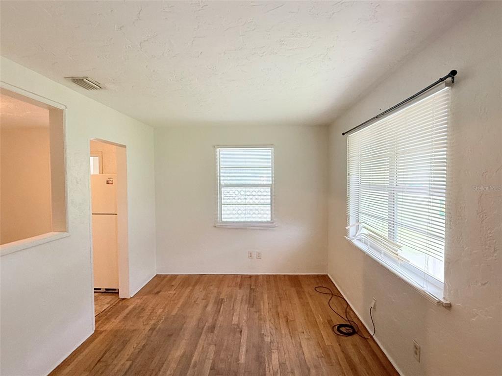An interior view shows a room with hardwood floors, a front door, and an open doorway — 5013 20TH STREET N, ST PETERSBURG, FL