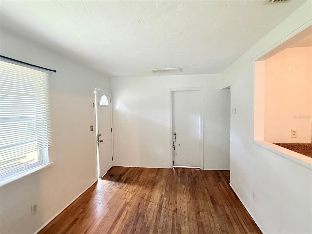 A room with hardwood floors, a large window with white blinds, and a white door — 5013 20TH STREET N, ST PETERSBURG, FL