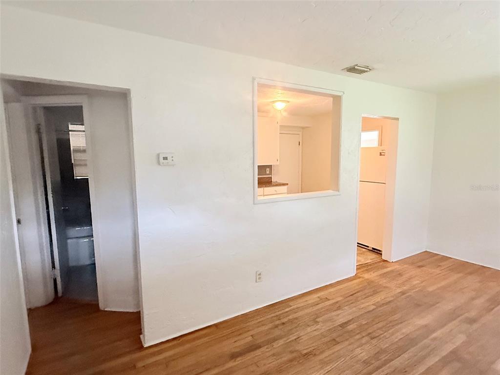 A room with hardwood floors, a wall cutout looking into a kitchen, and two doorways — 5013 20TH STREET N, ST PETERSBURG, FL