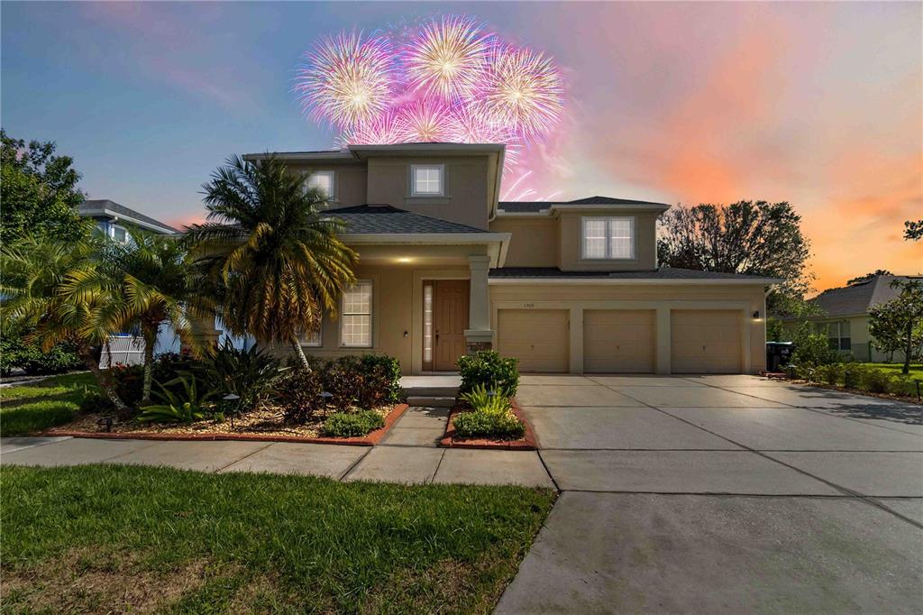 A two-story suburban house with a three-car garage and fireworks in the sky above — 13519 BICTON LANE, WINDERMERE, FL