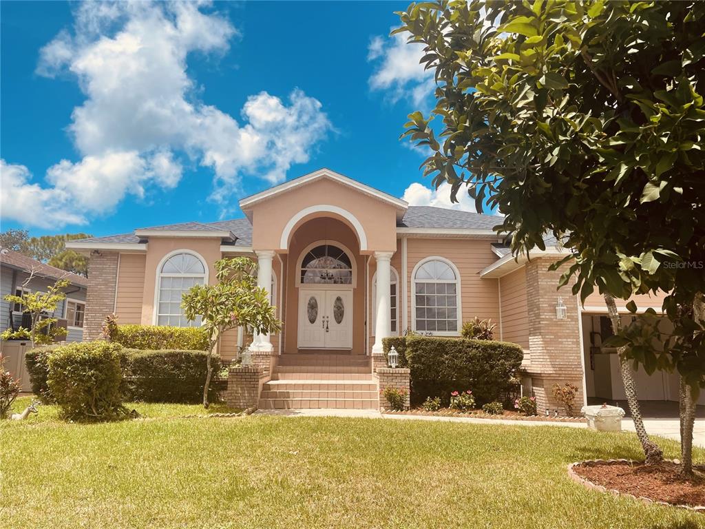 A single-story house with a peach-colored exterior, arched entryway, and a front lawn — 7116 PEBBLE BEACH LANE, SEMINOLE, FL