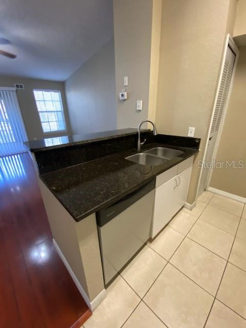 A kitchen features dark granite countertops, a double sink, and a stainless steel dishwasher — 5028 PARK CENTRAL DRIVE UNIT 2128, ORLANDO, FL