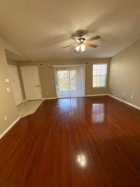 An empty living room features hardwood floors, a ceiling fan, and a sliding glass door — 5028 PARK CENTRAL DRIVE UNIT 2128, ORLANDO, FL