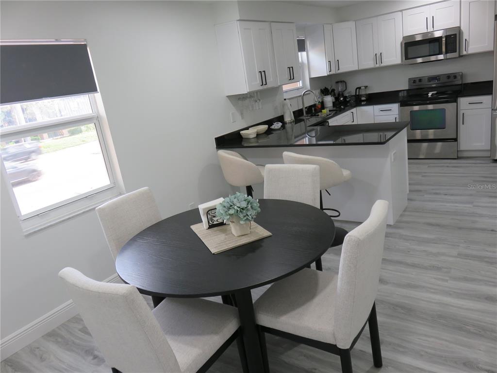 A dining area with a round table sits adjacent to a kitchen featuring white cabinets — 5401 SWEETWATER TERRACE CIRCLE UNIT 5401, TAMPA, FL