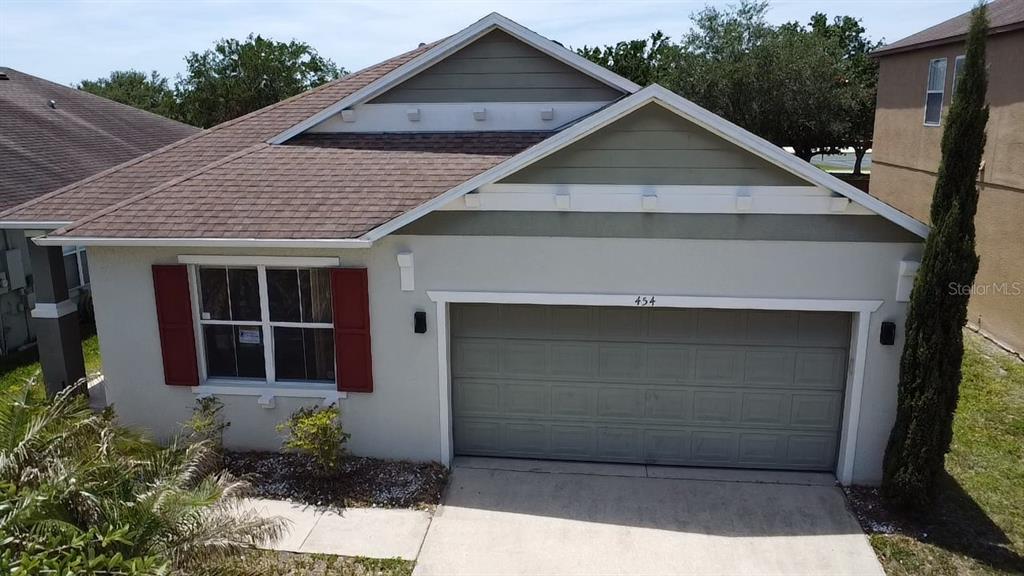 A single-story house with a two-car garage, light-colored stucco walls, and red window shutters — 454 JANICE KAY PLACE, KISSIMMEE, FL